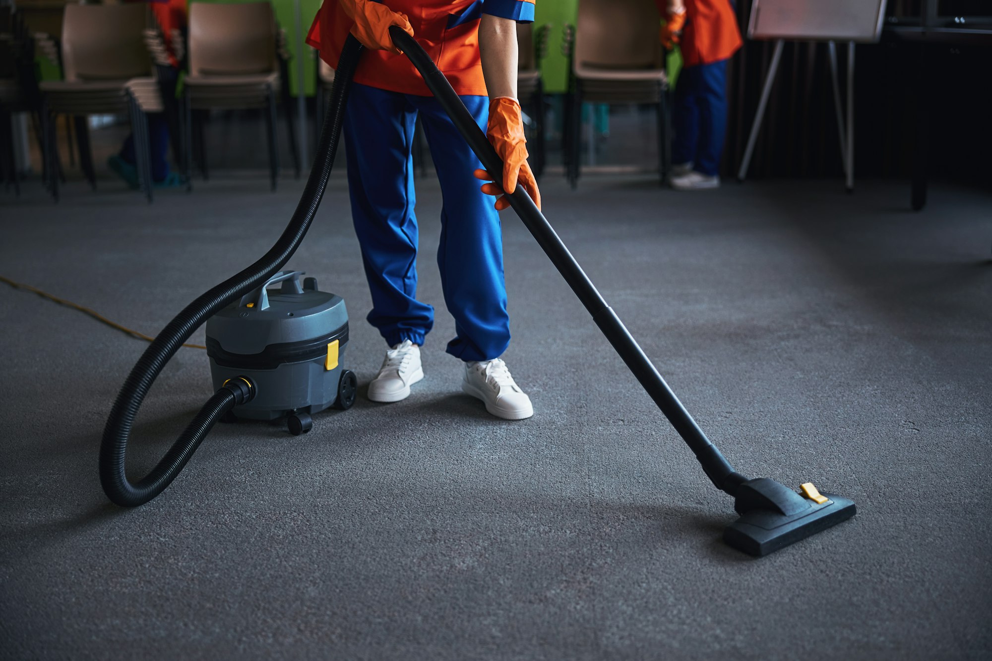 Cleaning lady using a canister vacuum cleaner